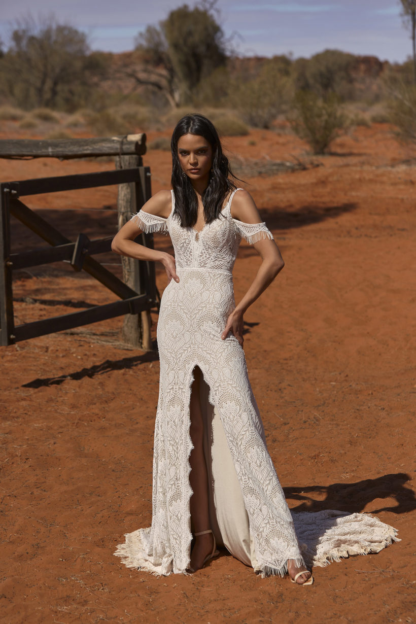 Vintage esküvőkre ajánljuk ezt a különleges matt csipkéből készült, elöl magasan sliccelt, sellő fazonú menyasszonyi ruhát az Evie Young 2021 évi "Outback" kollekcióból. A ruha bohó jellegét a különleges, lecsatolható ejtett váll biztosítja. Style: Rue. Elölről fotózva