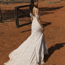 Vintage esküvőkre ajánljuk ezt a különleges matt csipkéből készült, elöl magasan sliccelt, sellő fazonú menyasszonyi ruhát az Evie Young 2021 évi "Outback" kollekcióból. A ruha bohó jellegét a különleges, lecsatolható ejtett váll biztosítja. Style: Rue. Hátulról fotózva