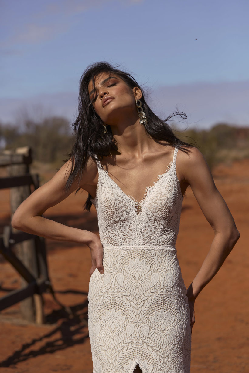 Vintage esküvőkre ajánljuk ezt a különleges matt csipkéből készült, elöl magasan sliccelt, sellő fazonú menyasszonyi ruhát az Evie Young 2021 évi "Outback" kollekcióból. A ruha bohó jellegét a különleges, lecsatolható ejtett váll biztosítja. Style: Rue.. Közelről fotózva