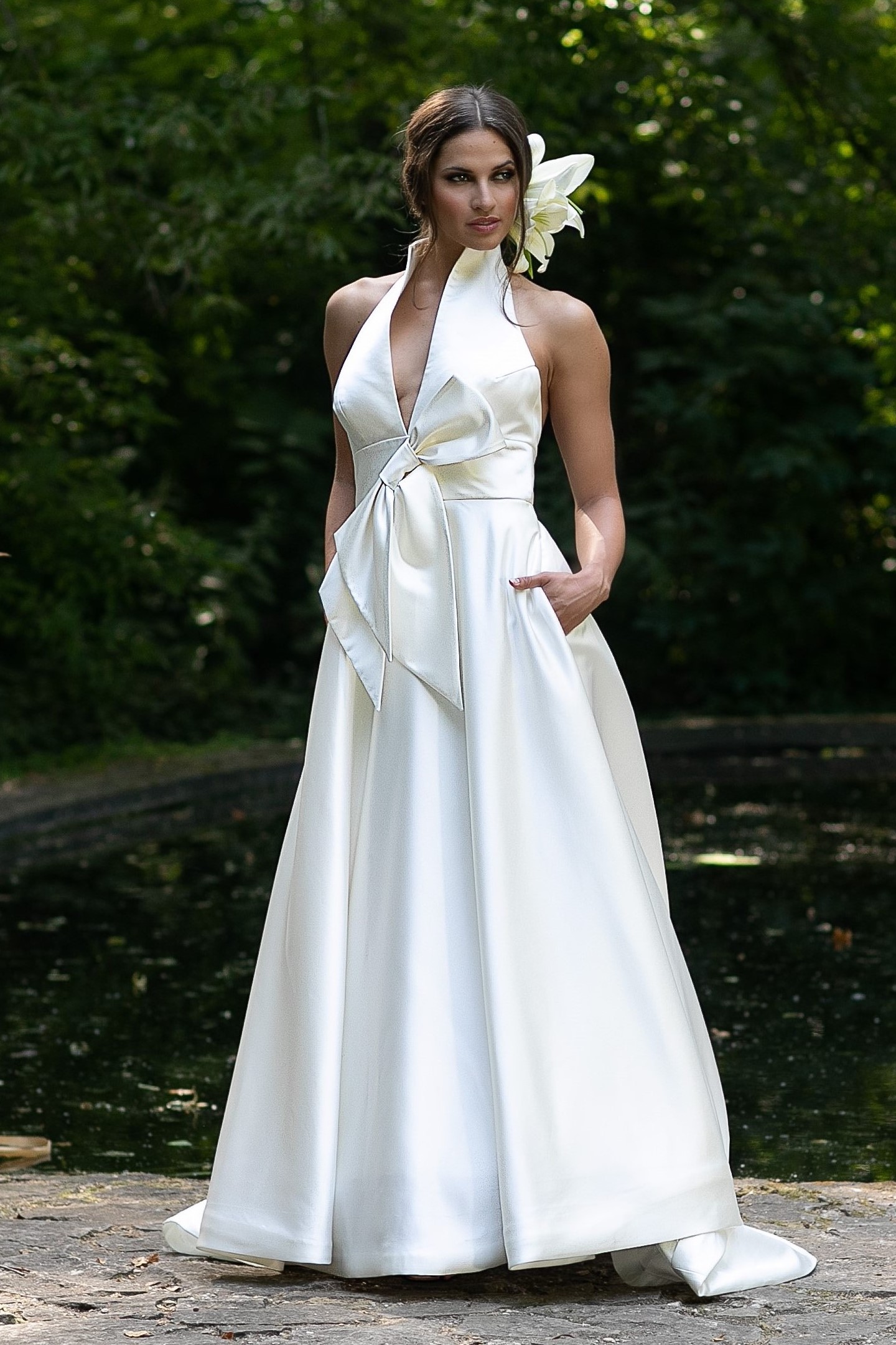 A voanlú, szatén menyasszonyi ruha halter nyakkal, rejtett zsebekkel és feltűnő masnival a derekán. Style: Jesus Peiro 956. Modell: Király Lili /Miss Balaton 2014, Diamond of the World 2017/ Image