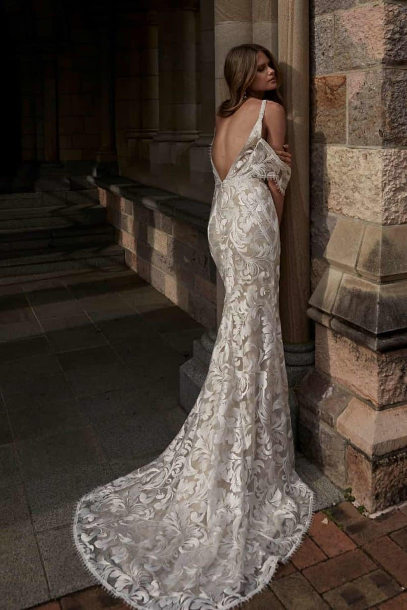 Klasszikusan elegáns, ugyanakkor romantikus sellő fazonú menyasszonyi ruha lecsatolható karpánttal. Az anyaga különleges hímzett virágminták.. Style: Evie Young "Saylor Hátulról