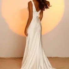 A vonalu, vállpántos V nyakkivágású lágy selyem menyasszonyi ruha mutatós uszállyal és széles övvel a derekán. Style: Jaxon a Madi Lane 2023 évi "Oasis" kollekcióból Hátulról